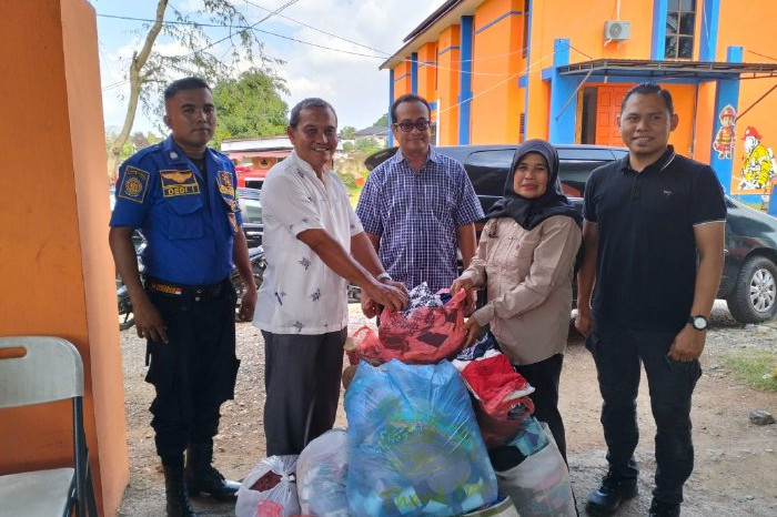 Kepala Diskominfo Aceh Besar, Muzakkir, SE yang didampingi Sekretaris Diskominfo, Khairul Huda, Skom, MM, menyerahkan bantuan pakaian layak pakai 